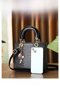 Black crocodile embossed tote bag next to a smartphone showing size and scale details