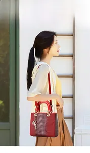 Detailed close-up of dark red crocodile embossed handbag with golden starfish charms