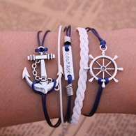 Detail showing nautical anchor bracelet with courage tag and rudder on wrist
