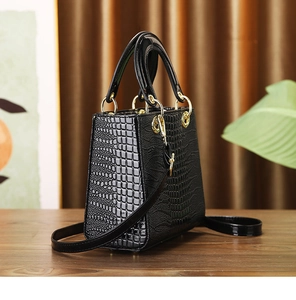 Detailed side view of black crocodile pattern handbag with gold hardware on wooden table