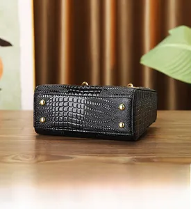 Detailed view of crocodile embossed leather handbag base with gold protective metal studs