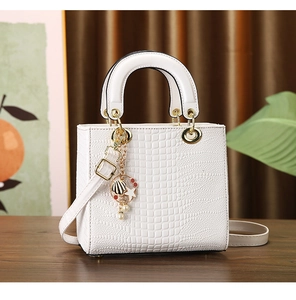 Close-up of white crocodile pattern handbag with gold hardware and pearl charm detail
