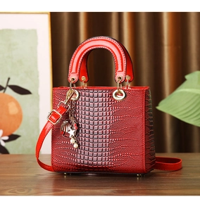 Detail of red crocodile texture handbag with gold charms and elegant top handle