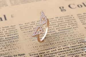 Macro shot of rose gold angel wing ring with pavé diamonds on vintage background