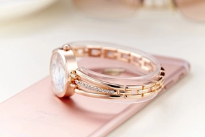 Detailed macro shot of rose gold metal watch strap with crystals on a phone surface