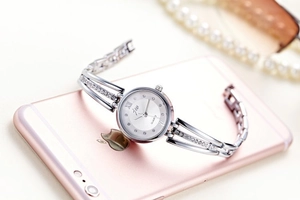 Detail showing elegant silver quartz watch with rhinestones on a pink smartphone