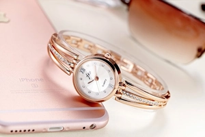 Close-up of rose gold rhinestone bracelet watch with white dial and stylish props