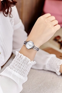 Close-up of elegant silver women's quartz watch with rhinestone steel strap on wrist