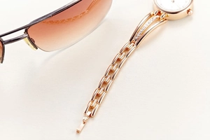 Close-up of rose gold rhinestone watch band paired with gradient sunglasses