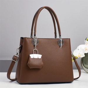 Detail of dark brown pebble grain leather handbag with silver hardware and mini charm