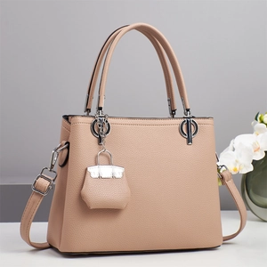Detail of warm apricot lychee grain leather handbag with silver hardware and mini charm