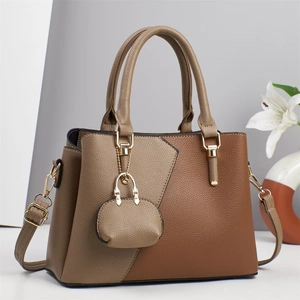 Sac à main élégant bicolore en cuir marron avec détails dorés et mini bijou de sac