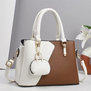 Détail d'un sac à main bicolore marron et blanc avec finitions dorées et porte-monnaie