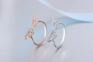 Close-up of rose gold and silver angel wing open rings with sparkling zircon crystals
