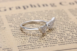 Detailed view of silver angel wing ring with crystals on vintage newspaper background