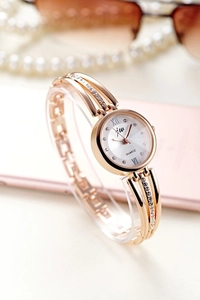 Close-up of gold tone JW watch featuring crystal bezel and white Roman numeral dial