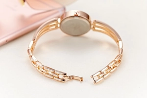 Detail shot of a rose gold women's watch with a metal link strap and open buckle