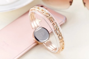 Elegant gold watch with round case shown from back view in a lifestyle setting with coffee