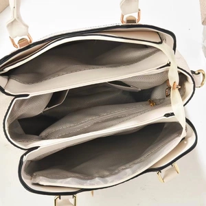 Detailed interior of a beige crossbody bag with grey chevron lining and compartments