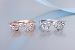 Close-up of rose gold and silver angel wing rings with sparkling zircon inlay details