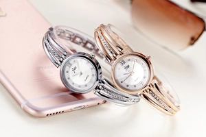 Detail of silver and rose gold rhinestone bangle watches with Roman numeral dials