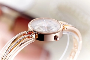Detailed macro view of rose gold watch with diamond-cut dial and rhinestone-set metal band