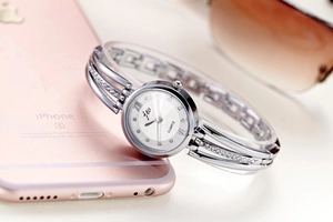 Macro detail of silver round watch dial with rhinestones and metal band with sunglasses