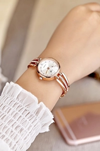 Detail of rose gold quartz watch with rhinestone strap worn on a female wrist