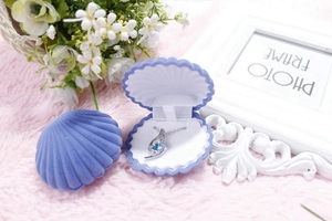 Detailed view of purple shell-shaped jewelry box with blue gemstone necklace on pink rug