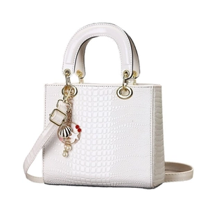 White crocodile embossed handbag with gold charms and detachable strap on white background