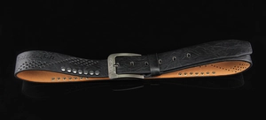 Macro shot of black textured leather belt with retro rivets and metallic buckle detail