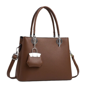 Caramel brown pebbled leather tote bag with top handles and mini charm detail