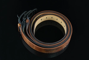 Close-up of rolled brown and black leather belts with antique buckles on black surface