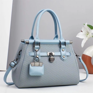 Elegant light blue woven handbag with long strap and lily decor in a clean studio setting