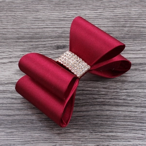 Close-up of red satin ribbon flower clip featuring sparkly rhinestone center