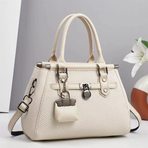 Elegant cream white satchel bag with woven texture, metal lock, and mini bag pendant