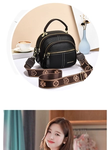 Detail of black pebbled leather bag with contrast stitching and patterned wide strap