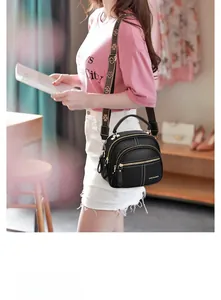 Side view of black pebble leather shoulder bag with floral wide strap and white stitching