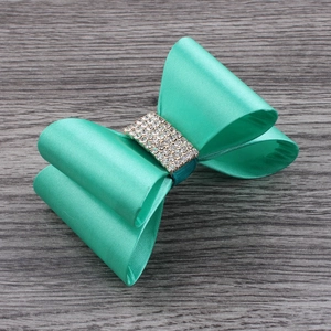 Detail of mint green satin bow hair clip with five rows of sparkling rhinestones