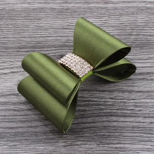 Detail view of olive green satin bow hair clip with luxury rhinestone center accent