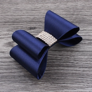 Detail of dark blue satin bow hair clip featuring five rows of sparkling white rhinestones