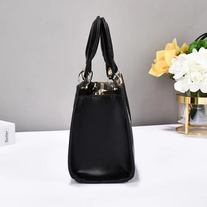 Side view of black faux leather handbag with gold rings and cylindrical top handles