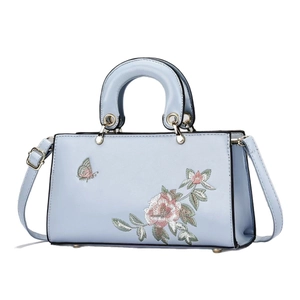 Elegant light blue crossbody handbag with floral embroidery and golden hardware accents