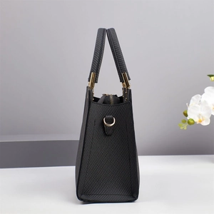 Detail of black crossbody bag with cross-grain leather texture and gold hardware accents