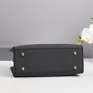 Detail view of woven tote bag base featuring protective gold metal feet and neat stitching