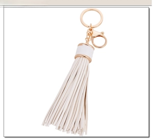 Close-up of white long tassel keychain with gold lobster clasp and circular metal ring