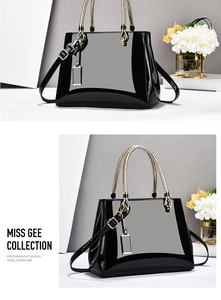 Detail of glossy black patent leather tote with gold woven handles and metal hardware