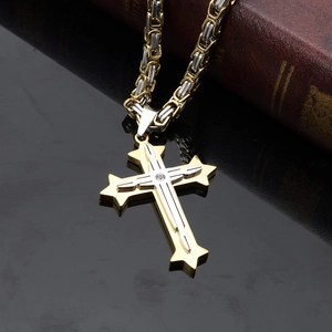 Détail du pendentif croix en acier bicolore sur une chaîne byzantine robuste