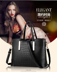 Detail of elegant black crocodile pattern handbag with gold hardware and shoulder strap