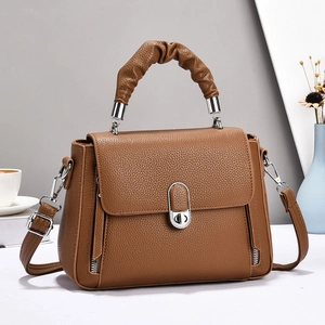 Close-up of brown lychee leather handbag with pleated handle and silver metal hardware